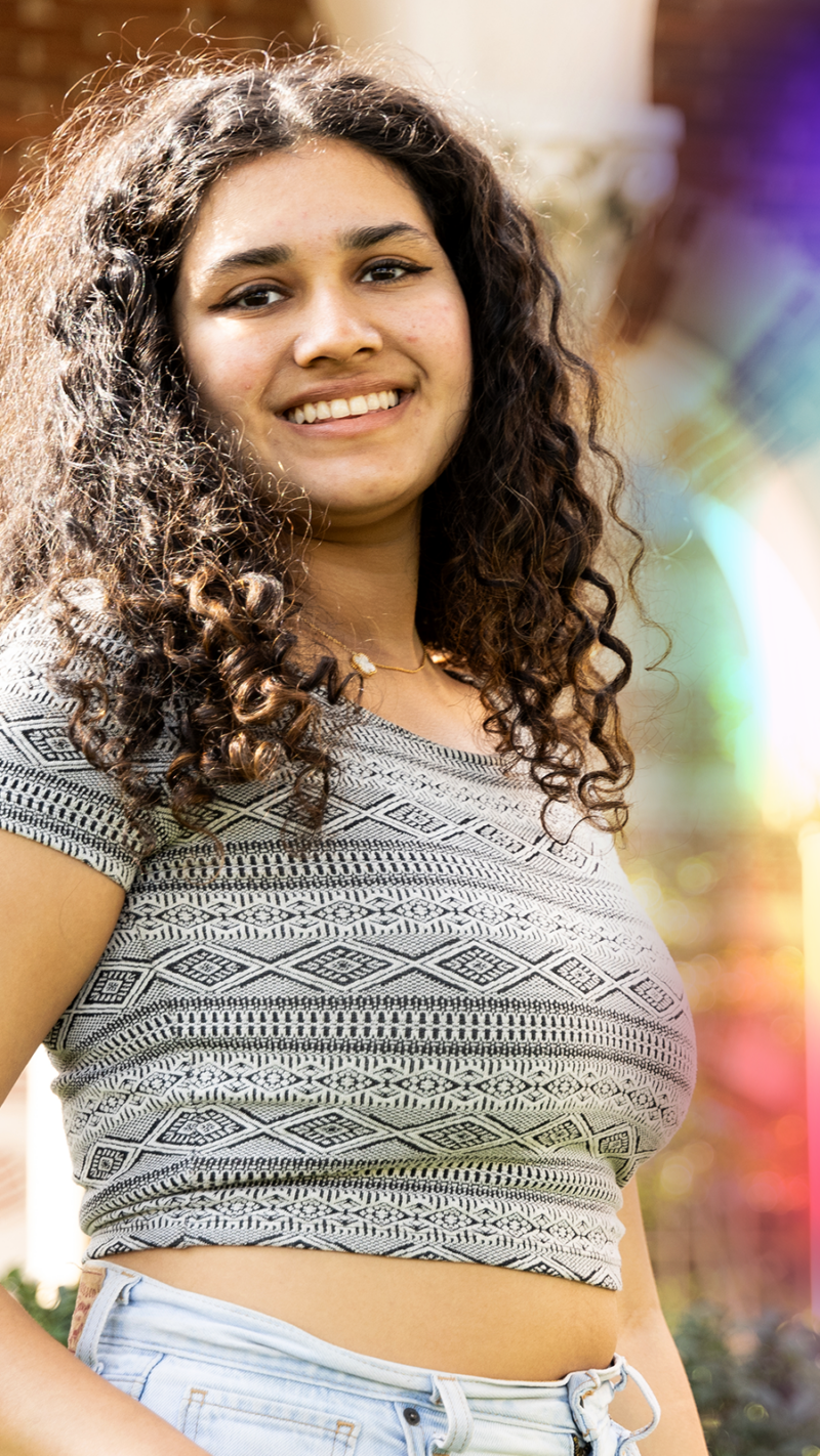 USC Dornsife female student looking at the camera smiling. Wearing a crop top and light jeans