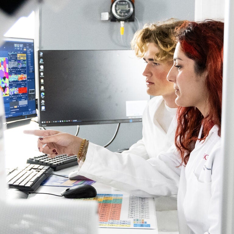 USC Dornsife Students pointing at a computer in a lab.