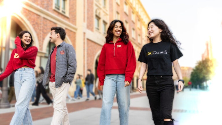 Group of four USC Dornsife student ambassadors walking through USC Village during the day