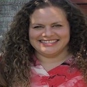 Photo of Alicia Chavez with long, curly hair wearing a red blouse and smiling.