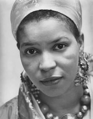 Portrait of Ntozake Shange facing the camera in black and white in traditional African jewelry