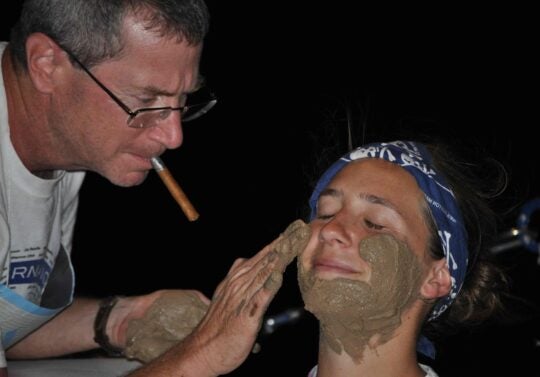 professor putting placing mud on face of student