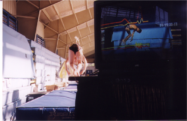 A photo of a diver jumping onto crash pads and being monitored by a computer.