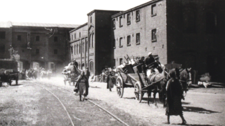 A picture of the forced removal of Polish Jews to a ghetto in Kutno, Poland. Here we see the site of the ghetto, an abandoned sugar factory. Horse drawn carts, piled high with furniture and belongings, trail into the courtyard. Photographed by Wilhelm Hansen. Courtesy of Jüdisches Museum Rendsburg in der Stiftung Schleswig-Holsteinische Landesmuseen Schloss Gottorf.