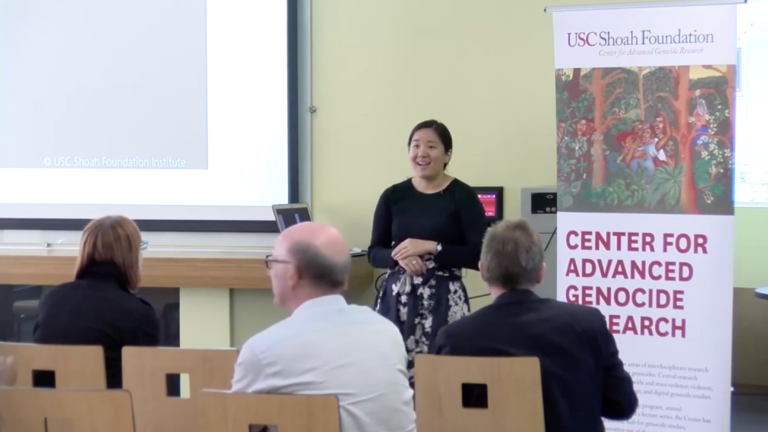 Screenshot of Kimberly Cheng presenting. She smiles, hands crossed over one another.