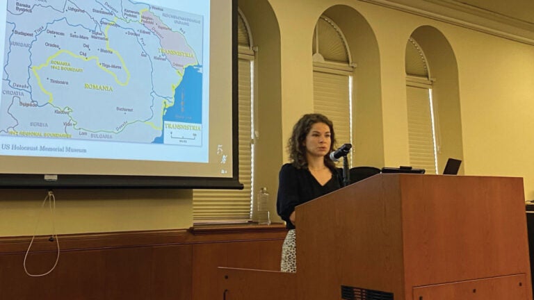 Lilia Tomchuk stands behind a podium in Doheny Library. A map of the Transnistria area is shown on the projected presentation slides.