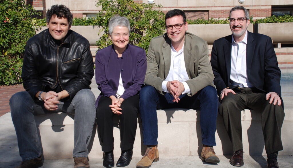 The Holocaust Geographies Collaborative sit on the edge of a fountain in front of Leavey Library.