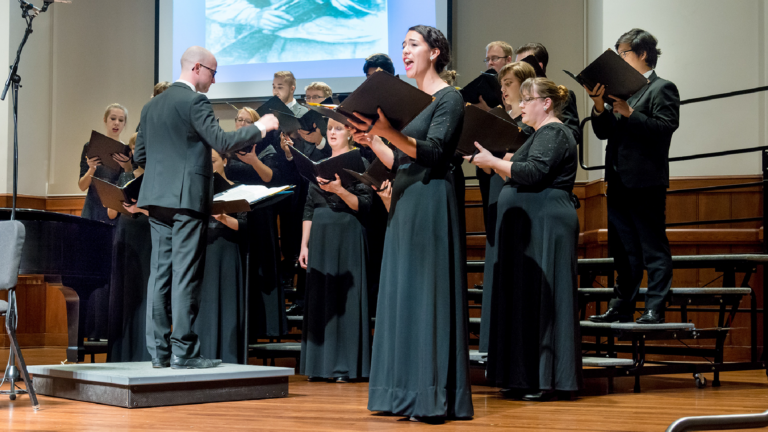 The USC Thornton Chamber Singers, dressed in all black, perform on-stage.