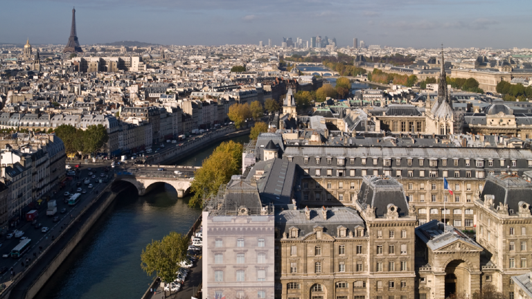 Scenic photo of Paris, depicting the Seine River. The Eiffel Tower can be seen in the far distance.