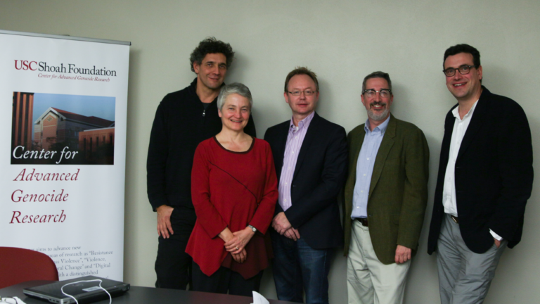 The Holocaust Geographies Collaborative pose with the Center Director next to a center banner. From left to right: Alberto Giordano, Anne Kelly Knowles, Wolf Gruner, Paul Jaskot, and Tim Cole.