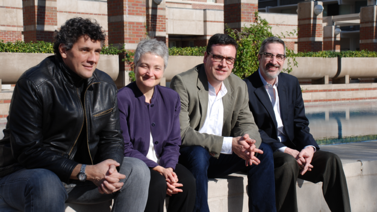 The Holocaust Geographies Collaborative smile against the bright sun, perched on the edge of Leavey Library’s fountain.. From left to right: Alberto Giordano, Anne Kelly Knowles, Tim Cole, and Paul Jaskot.