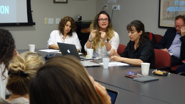 The 2017 to 2018 Latin American Research Week Team sit on either side of tables pushed together in a USC History building conference room. From left to right: Daniela Gleizer Salzman, Lorena Avila Jaimes, Nancy Nicholls Lopeandía, and Wolf Gruner. Various laptops, notes, cups, and food are scattered across the table.