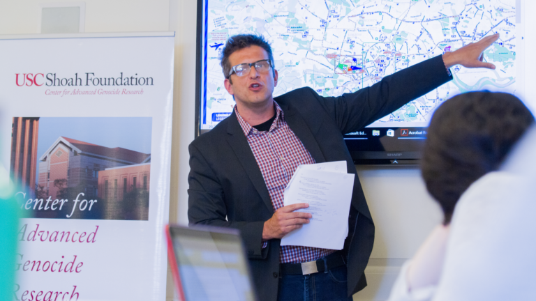 Photo of Piotr Florczyk pointing to a map displayed on a screen.