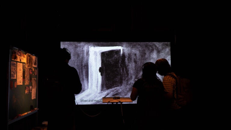 Silhouette of people looking at artwork.