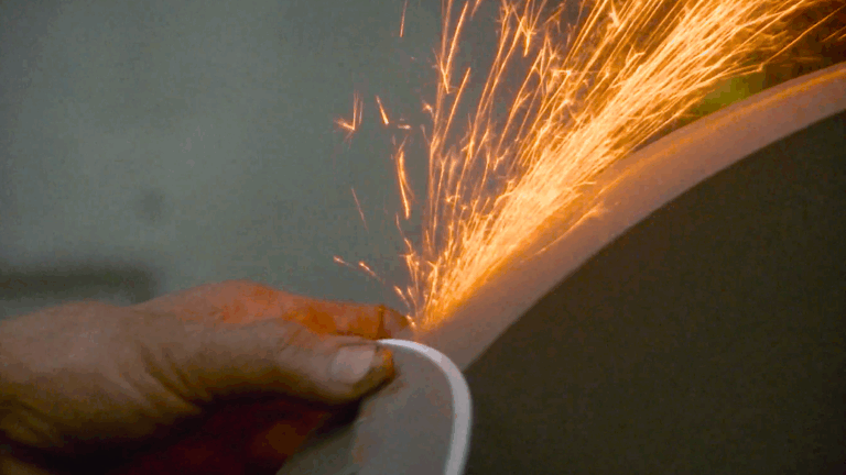 Sparks fly as a metal disc is held to a sharpening stone.