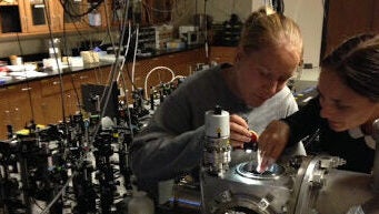 Two young women working on a large instrument