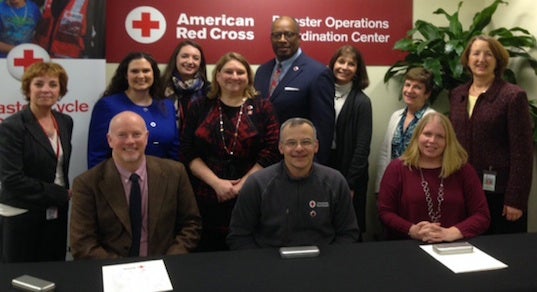 Group photo of people posing with an "American Red Cross" banner in the background.