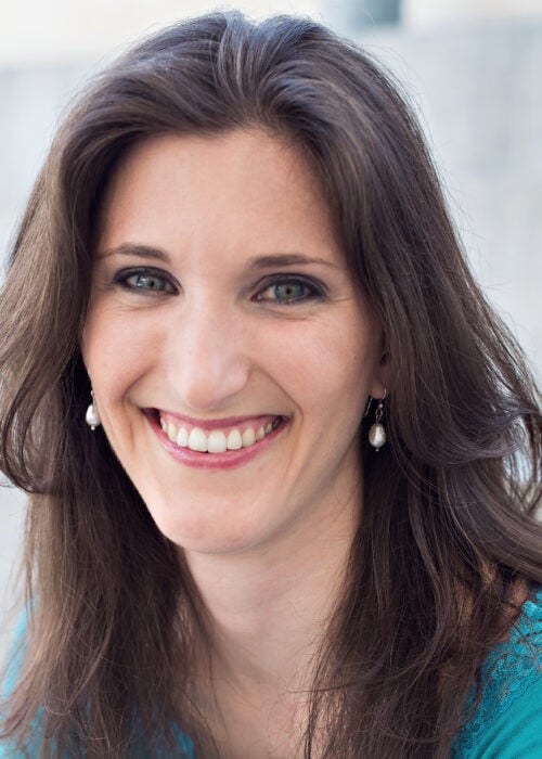 A smiling woman with long brown hair in a professional portrait.