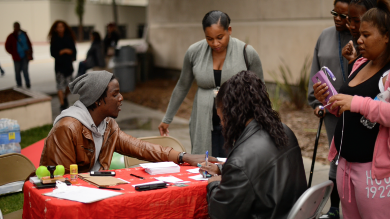 seated man speaks to people gathered around table