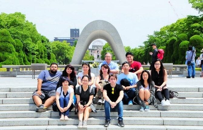 Students sit in a group outdoors on steps in Japan.