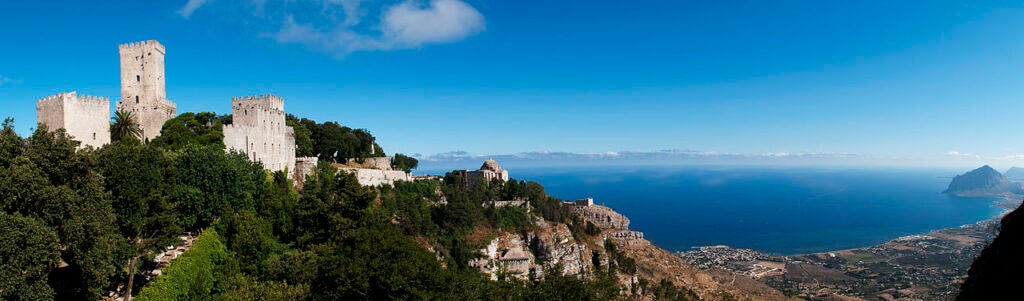 Stone castle on a hill with a blue ocean behind it