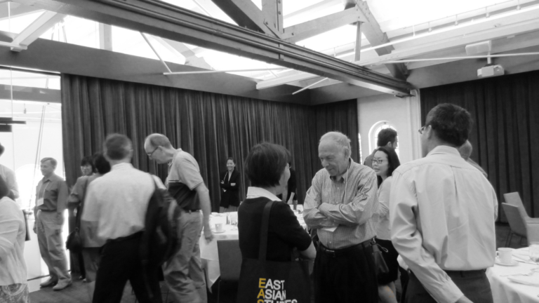 A black and white photo of various faculty having conversations. The EASC logo is colored yellow.