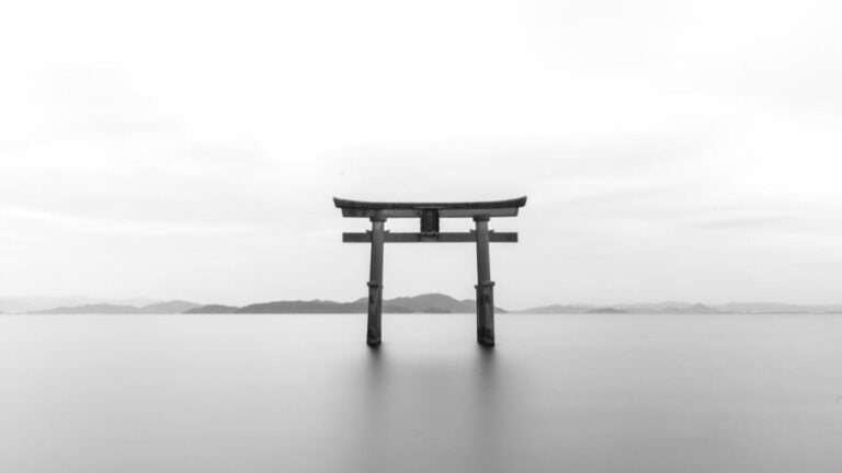 A black and white photo of a lone torii gate in the middle of nowhere.