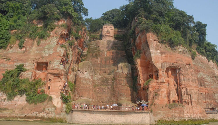 A large statue carved into the side of a cliff.
