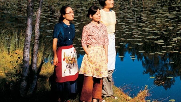 3 women standing by a lake.