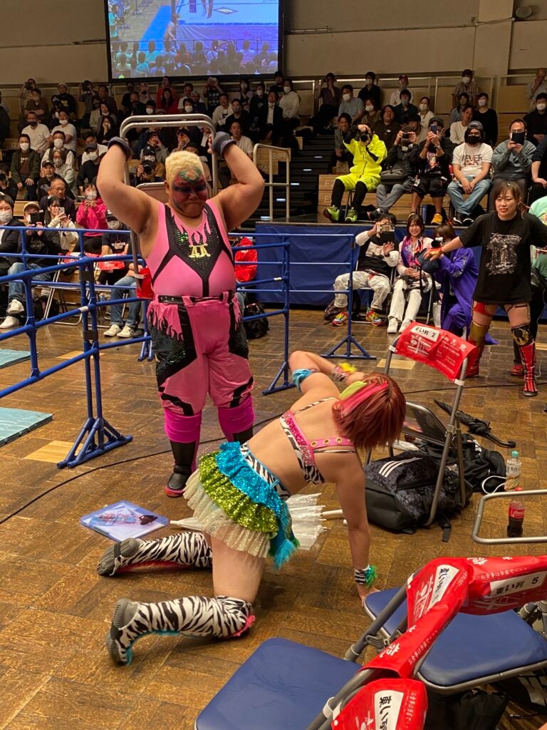 A female wrestler is about to throw a chair on another wrestler