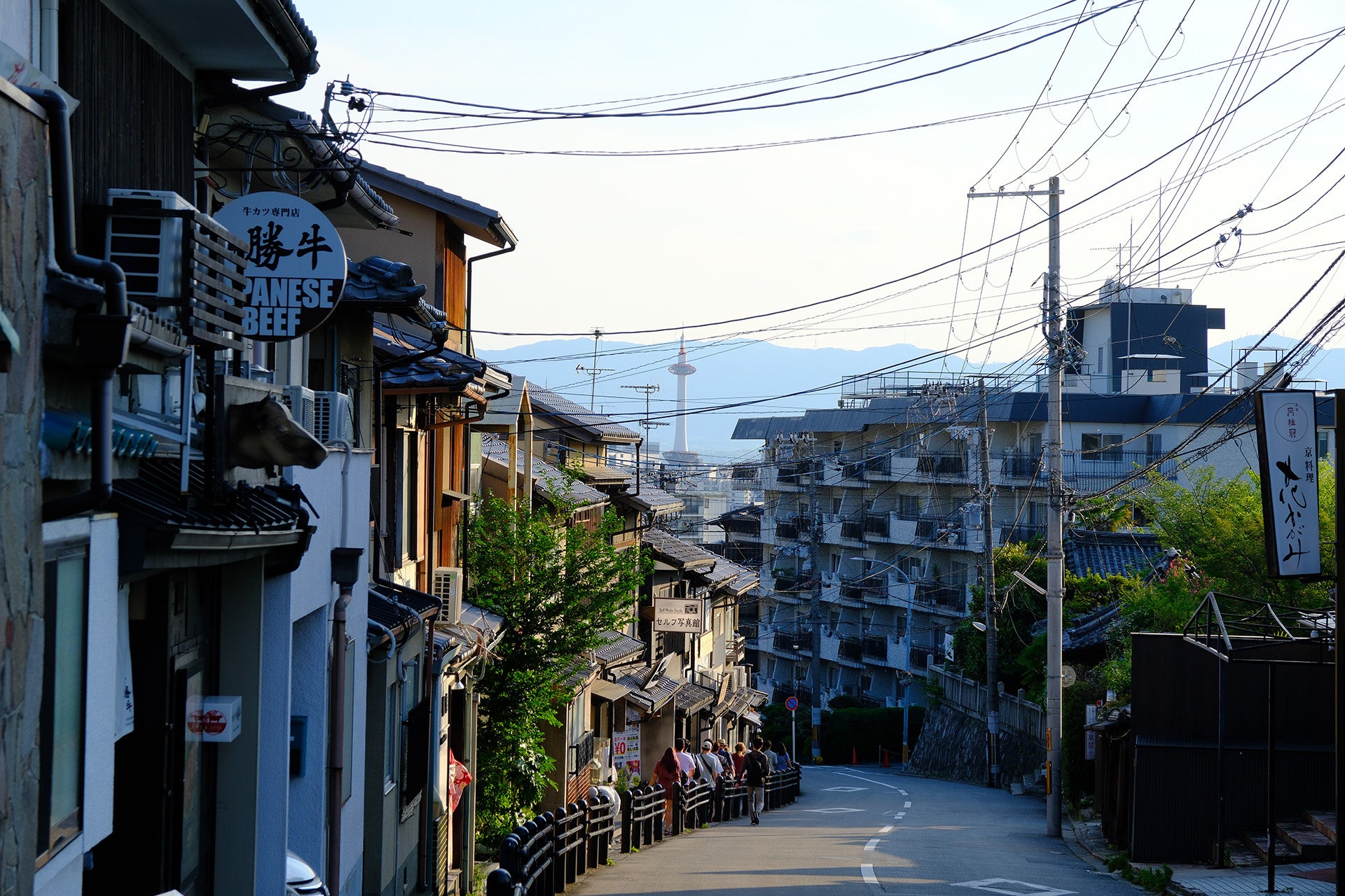 A downhill Japanese street lined with small shops and apartments.