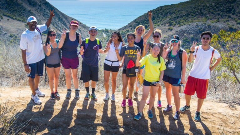 professor and students hiking and throwing up the fight-on sign