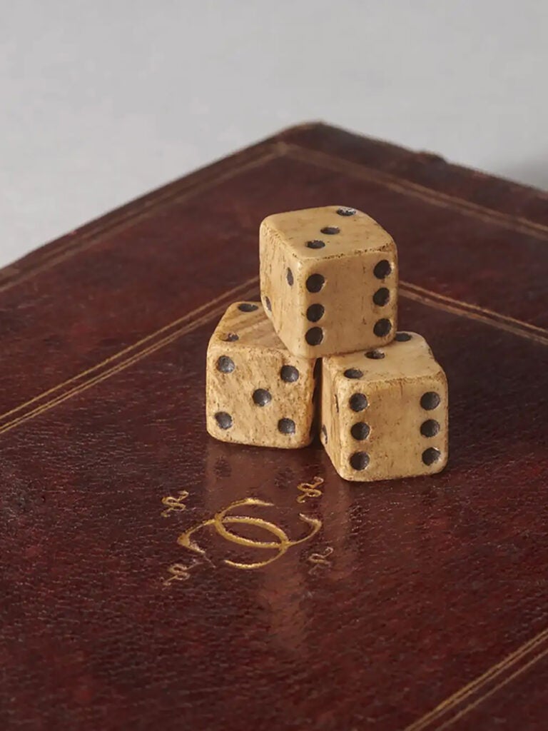 three bone dice stacked on top of a manuscript