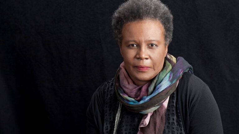 Claudia Rankine looks to the viewer. Her expression is serious and determined.