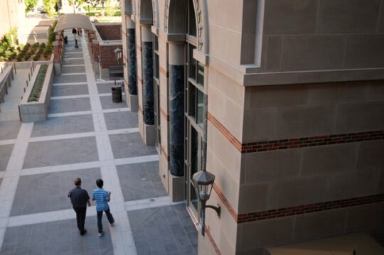 In the Tutor Student Union, two individuals walk together. This is an aerial view.