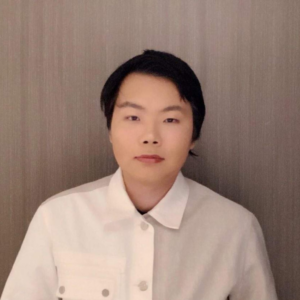 A headshot of a person of Asian descent with short black hair wearing a white button down shirt