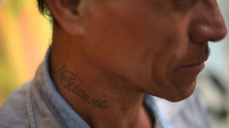 A person shows the side of their cheek and neck with tattoo that reads: Mexicano.