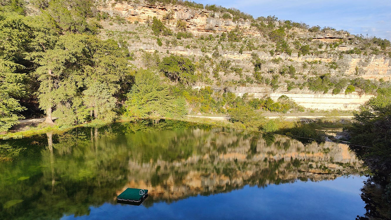 A blue lake with a reflection of the landscape in the Texas hill country 