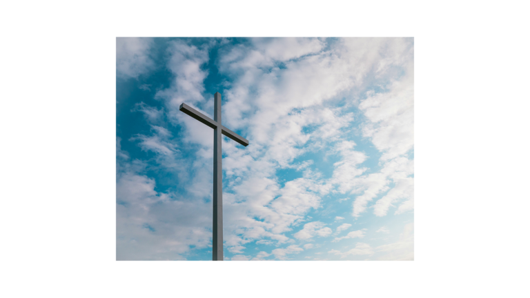 A cross against a blue sky with white clouds