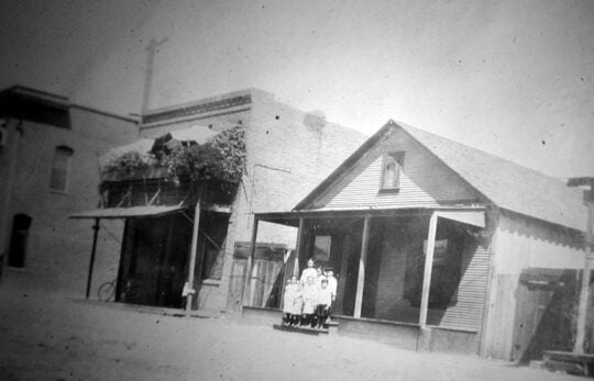 Black and white photo of Soo Hoo family home on Apablasa Street with seven family members on the front step.