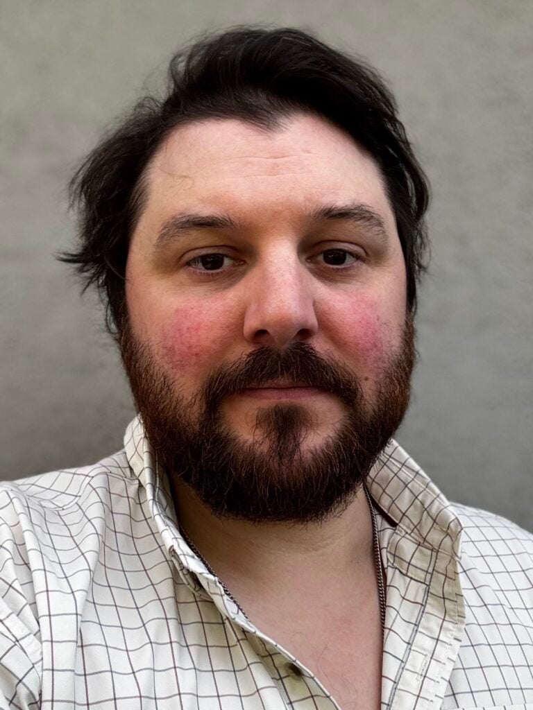 Man with beard in collared shirt with windowpane design.