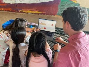 Dr. Adam MacLean assists WonderKids’ students at Norwood St. Elementary with figuring out the best balance of blood cells in a stem cell simulation game created by his research group.