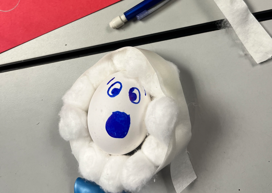 An egg with a scared face painted on surrounded by cotton swabs