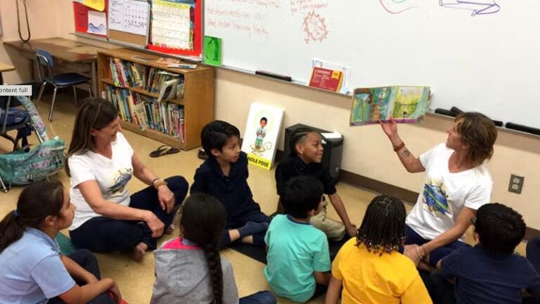 Kids looking at someone reading them a book