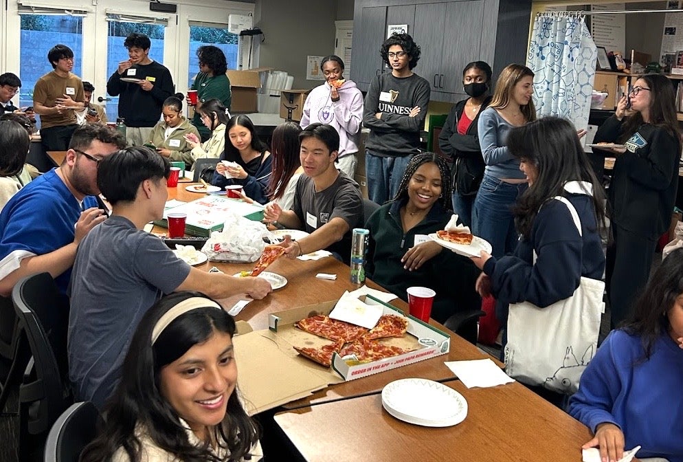 Students all together socializing and eating Pizza