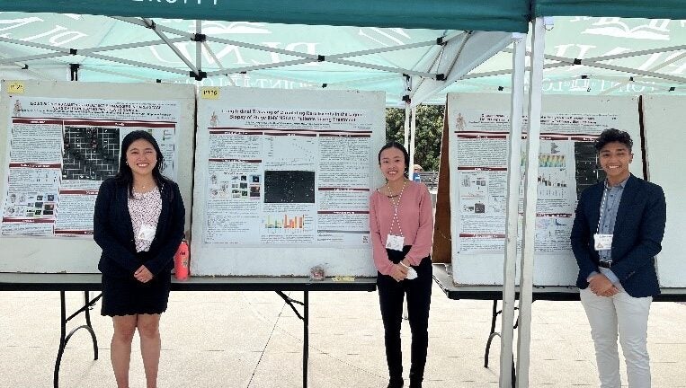 students standing under an awning with research presentation