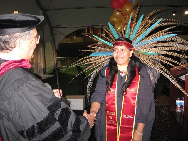 A graduate shakes hands with a professor.