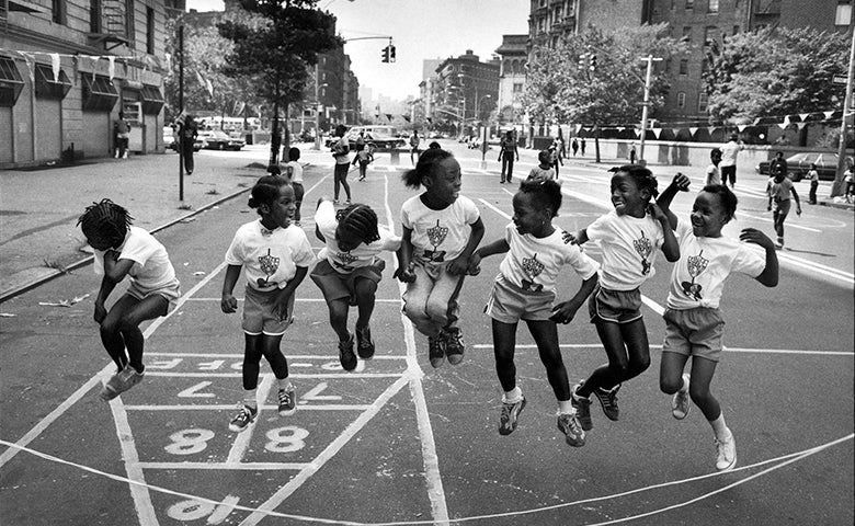 A group of kid jump rope together in a street.