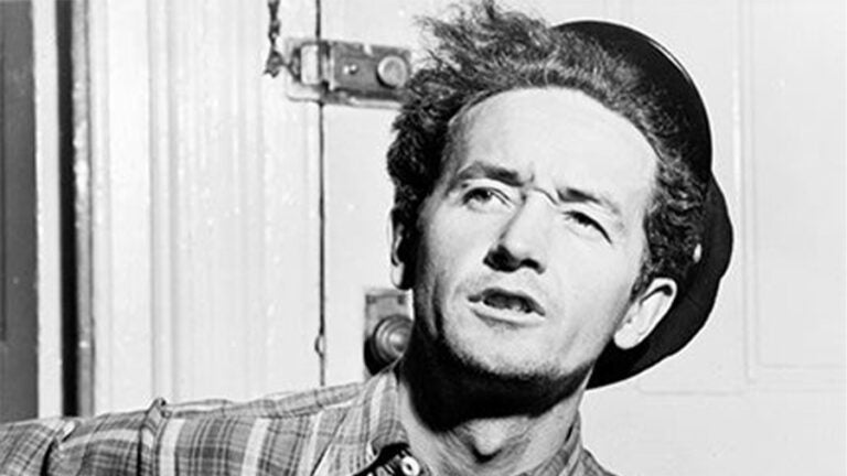 A black and white photo of Woody Guthrie