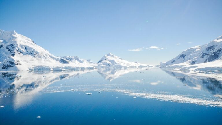 A glacier in Antarctica and its reflection in the water.